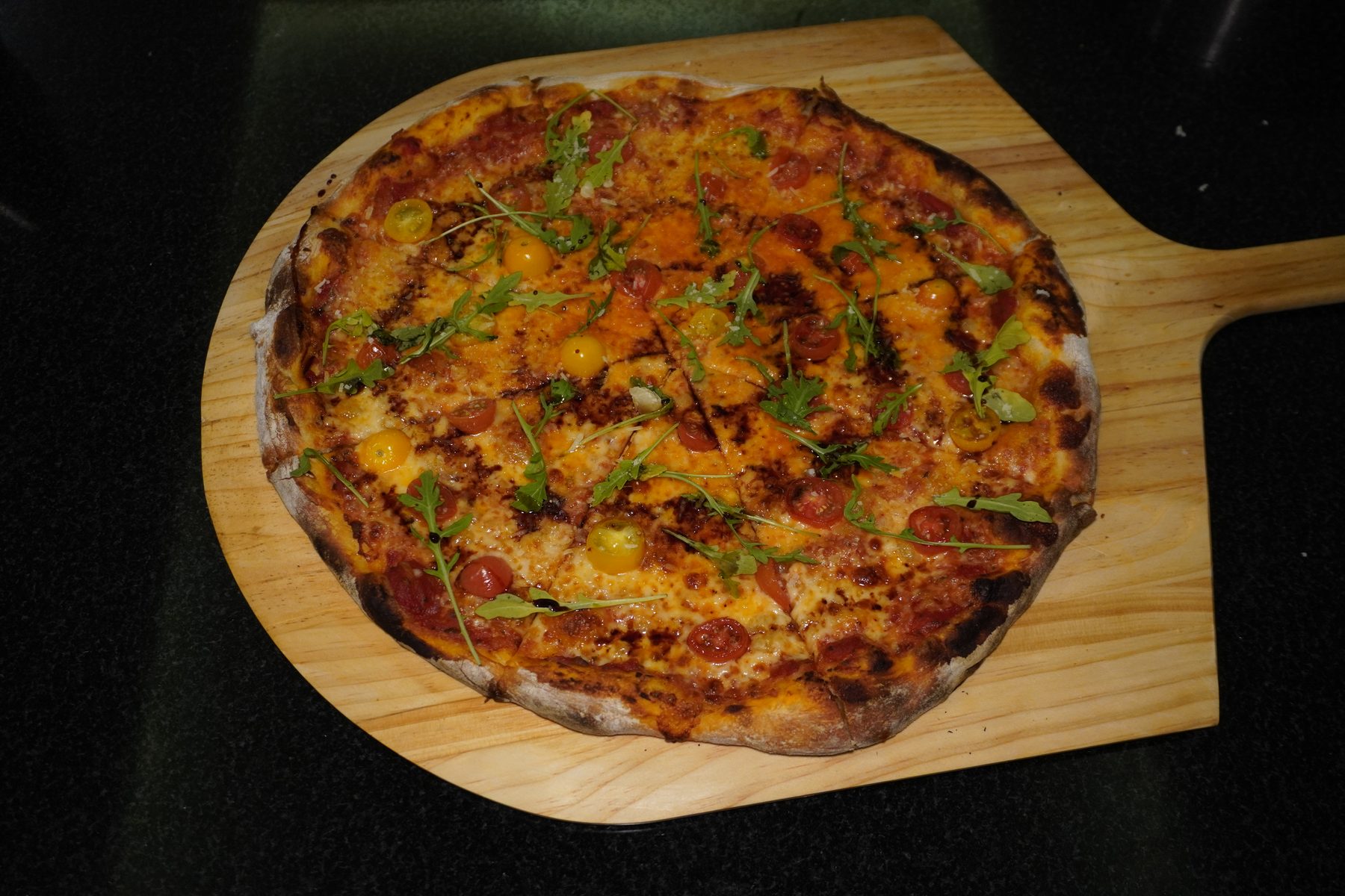 Pizza estilo NY con tomate cherry y arúgula recién horneada